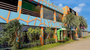 Un edificio con fachada geométrica de colores, un letrero que dice 'Collection' y una estructura verde con la etiqueta 'Quick Charge'.