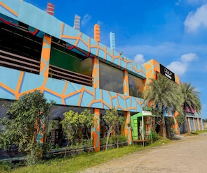 Um edifício com fachada geométrica colorida, uma placa com a inscrição 'Collection' e uma estrutura verde identificada como 'Quick Charge'.