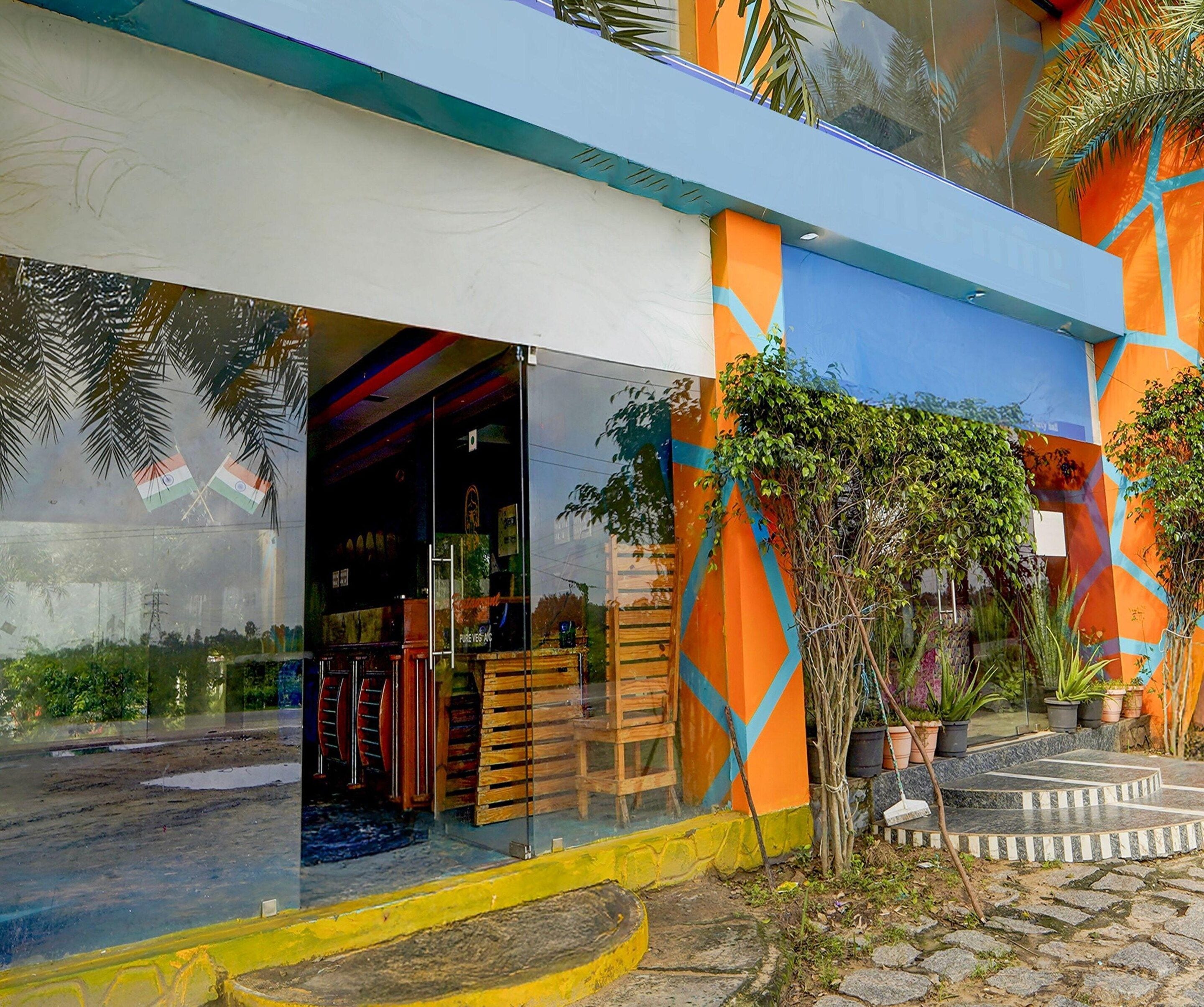 A building with a glass entrance, wooden furniture inside, and a colorful exterior with geometric patterns.