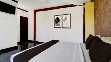 A hotel room with a bed, a door, and two framed pictures on the wall.