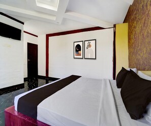 A hotel room with a bed, a door, and two framed pictures on the wall. - Classic Navagiraga Resort & Hotel (Sirkazhi)