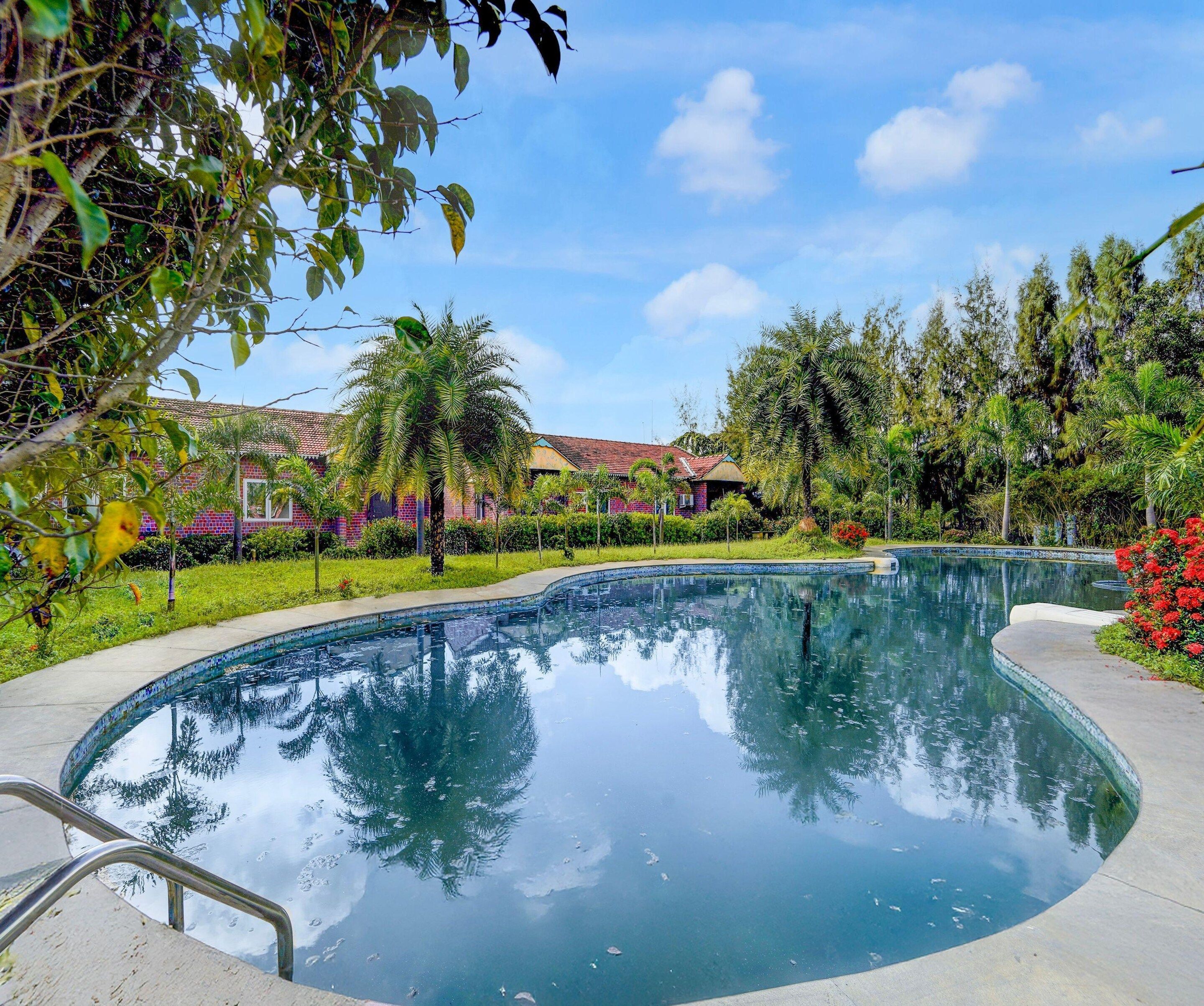 A swimming pool with a clear view of the surrounding greenery and a building with a tiled roof.