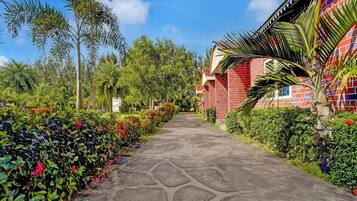 A pathway leading to a building with a red brick facade and a tiled roof.