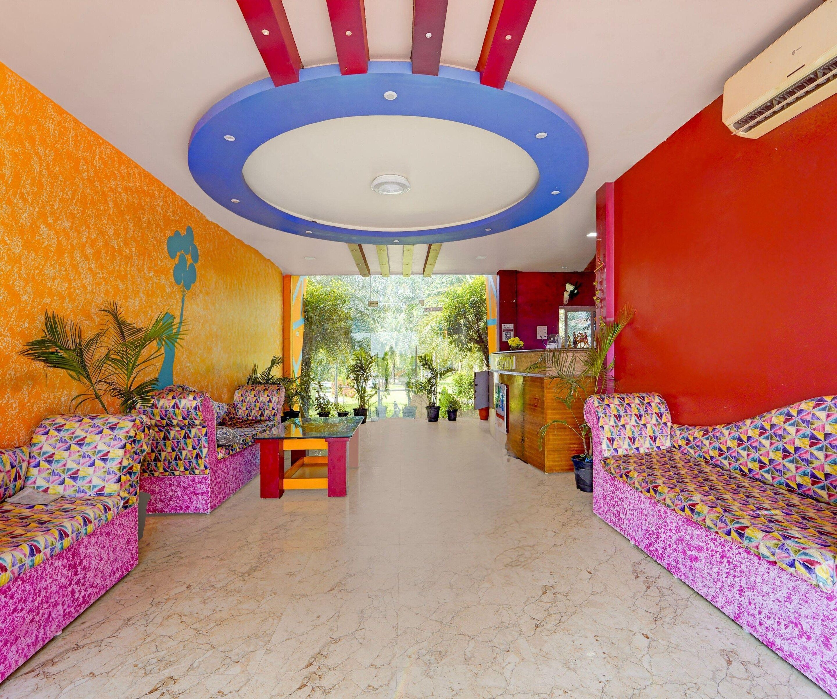 Vestíbulo de hotel con sofás coloridos, un mostrador de recepción y vistas a zonas verdes.