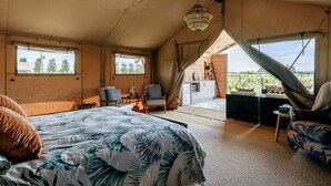 Un alloggio in tenda con un letto, una zona salotto e vista sulla natura.