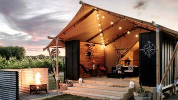 A cozy outdoor tent with a fire pit, seating area, and a compass.
