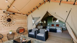 Un alloggio in tenda dotato di area ristorazione, un letto e un bagno.