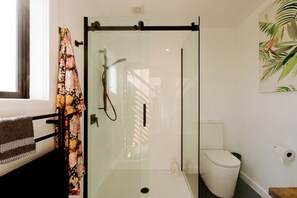 A glass-enclosed shower stall with a handheld showerhead, a toilet, and a towel rack with a towel. - Beautiful Safari Tent on a Gorgeous Vineyard near Hastings, North Island (Hastings)