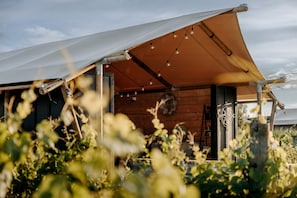A rustic wooden cabin with a large awning, a compass, and string lights.