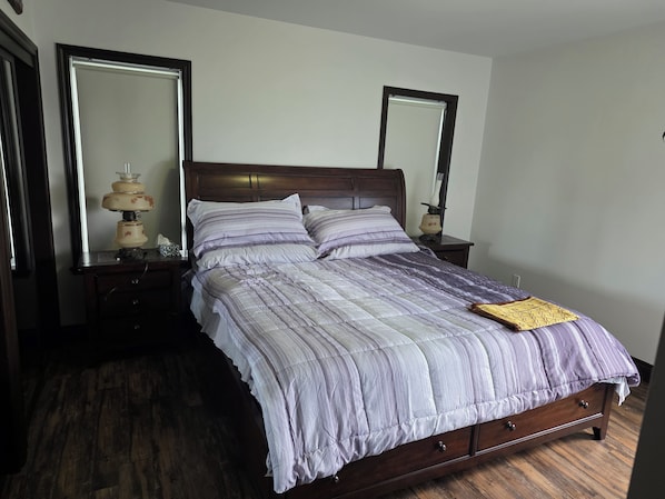 A bed with a wooden frame, two nightstands with lamps, and a mirror on each side.