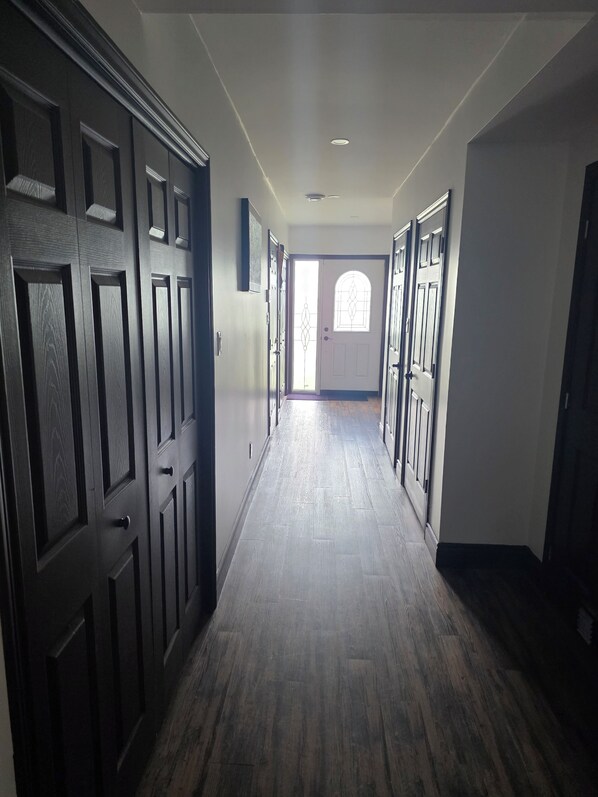 A hallway with wooden flooring and dark wooden doors on both sides.