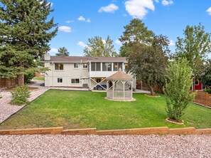 A two-story residential building with a covered patio area and a well-maintained lawn.