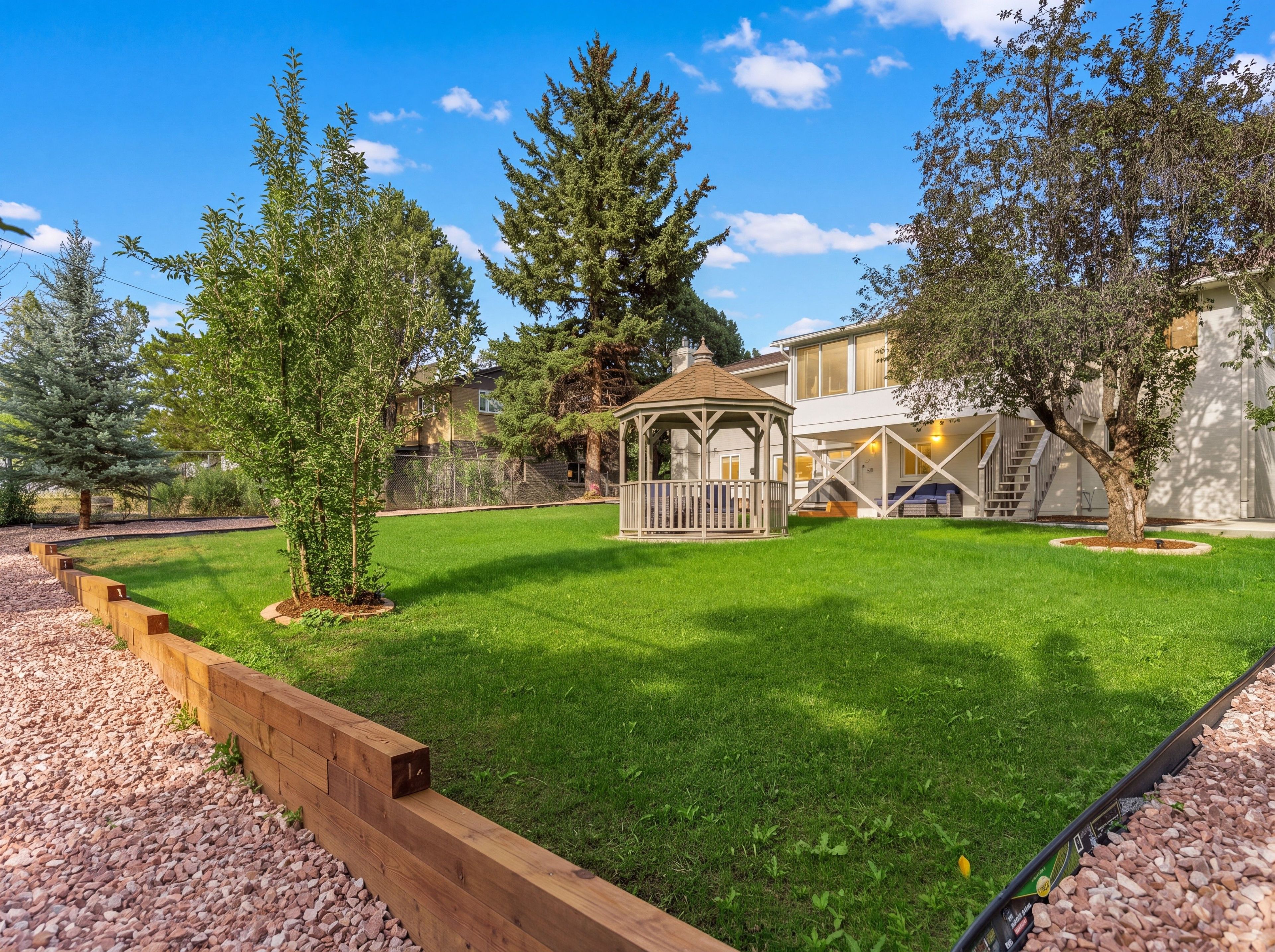 A well-maintained backyard with a wooden deck, a gazebo, and a lawn.