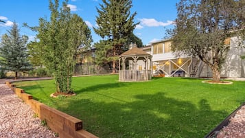 A well-maintained backyard with a wooden deck, a gazebo, and a lawn.