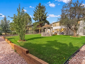 A well-maintained backyard with a wooden deck, a gazebo, and a lawn.
