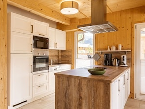 A modern kitchen with white cabinetry, stainless steel appliances, and a central island. - One-bedroom Cabin (Sankt Georgen am Kreischberg)