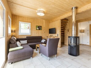 A wooden interior with a sofa, armchair, TV, and a wood-burning stove. - One-bedroom Cabin (Sankt Georgen am Kreischberg)