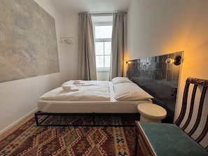 Ein Hotelzimmer mit einem Bett, einer Toilette, einem gemusterten Teppich und einer Wand mit einer Lampe.