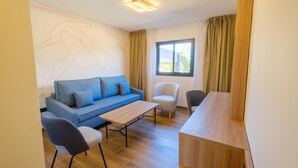 Uma sala de estar moderna com um sofá azul, uma mesa de centro de madeira e duas cadeiras.