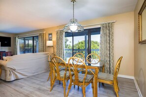 Ein Zimmer mit einem Bett, einem Esstisch mit Stühlen, einer Chandelüster und Blick durch eine Glastür.