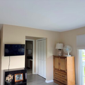 A room with a television, a cabinet, a fan, and a window. - Marsh View Condo Steps to Beach Boardwalk - Pet Friendly (Saint Helena Island)