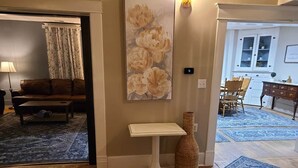 Una stanza con pavimento in legno, un tavolo rotondo bianco, un vaso e un dipinto di fiori.