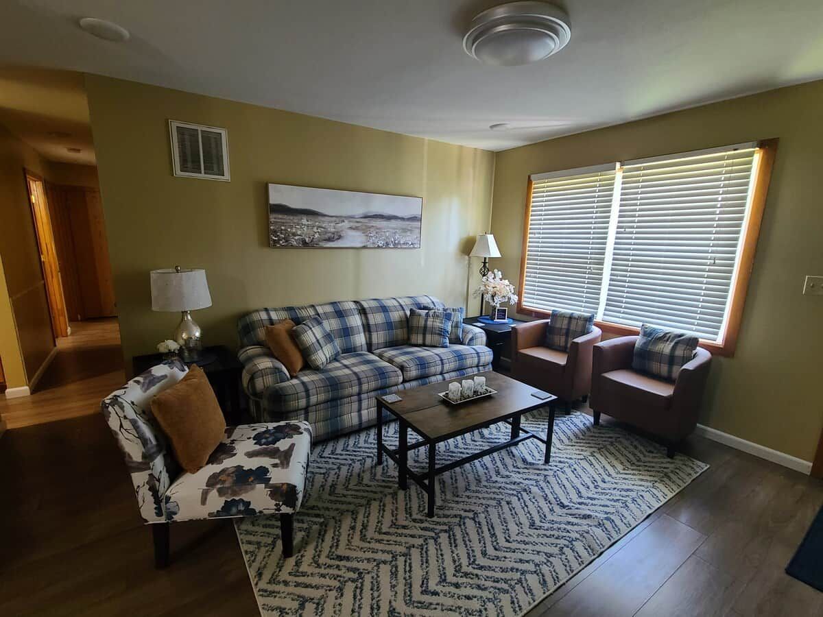A living room with a sofa, armchair, coffee table, and a painting on the wall.