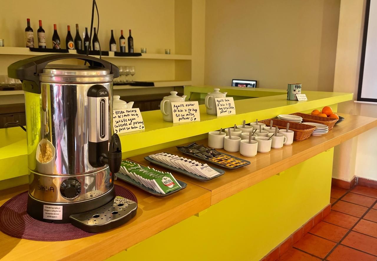 A coffee station with a coffee maker, cups, and a display of coffee packets.