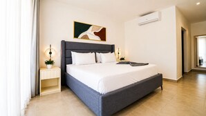 A modern hotel room with a large bed, bedside lamps, a small table with a plant, and a painting on the wall. - Wake Up to the Ocean: 3-Bedroom Palmera · Beach & Pool (Punta Cana)