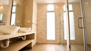 A modern bathroom with two large white sinks, a glass shower enclosure, and a large window providing natural light. - Wake Up to the Ocean: 3-Bedroom Palmera · Beach & Pool (Punta Cana)