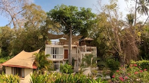 A multi-story building with balconies, surrounded by lush greenery and trees. - Casa Parota (Ixtapa Zihuatanejo)