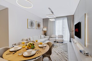 A modern living room with a dining area, a sofa set, a TV, and a fruit bowl on the table. - Elegant 2BR at VidaDubai Mall Prime Downtown Location (Dubai)