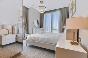 Ein modernes Schlafzimmer mit einem großen Bett, Nachttischen, einem Spiegel und Blick ins Freie.