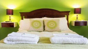 A neatly made bed with two pillows, two bedside tables with lamps, and a green wall. - Lovely 2-bedroom bed & breakfast with AC in Buenos Aires (Buenos Aires)
