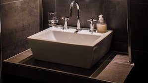 A bathroom with a rectangular mirror, a sink, a faucet, a soap dispenser, and a glass. - Lovely 2-bedroom bed & breakfast with AC in Buenos Aires (Buenos Aires)