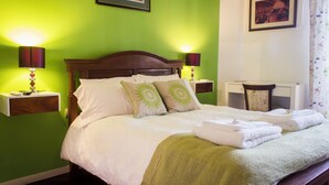 A neatly made bed with white linens and green pillows, two bedside lamps, and a framed picture above the bed. - Lovely 2-bedroom bed & breakfast with AC in Buenos Aires (Buenos Aires)
