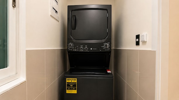 A compact, black, wall-mounted laundry machine with a control panel and an ENERGY GUIDE sticker. - The Ocean Is Your Window: 2-Bedroom Apartment at Playa Palmera (Punta Cana)