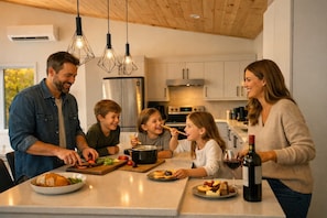 Una cocina moderna con una isla central, electrodomésticos de acero inoxidable e iluminación colgante.