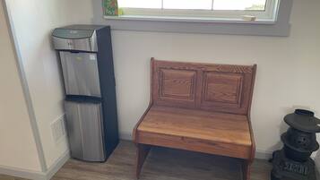 A room with a wooden bench, a water dispenser, and a stove.