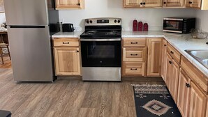 Une cuisine avec des meubles en bois, un réfrigérateur en acier inoxydable, une cuisinière à gaz et un four à micro-ondes.