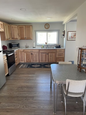 A kitchen with wooden cabinets, a microwave, a stove, a sink, and a dining table with chairs.