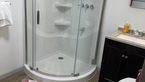 Une salle de bain dotée d’une douche à parois de verre, de toilettes, d’un lavabo avec un plan de travail et d’un miroir au-dessus du lavabo.