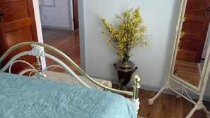 Une chambre à coucher avec un lit, un miroir et un vase de fleurs.