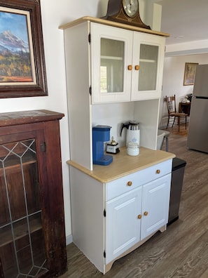 A kitchen with white cabinets, a coffee maker, and a clock on the wall.
