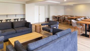 Ein moderner Loungebereich mit Sofas, einem Couchtisch und einem Essbereich mit Tischen und Stühlen.