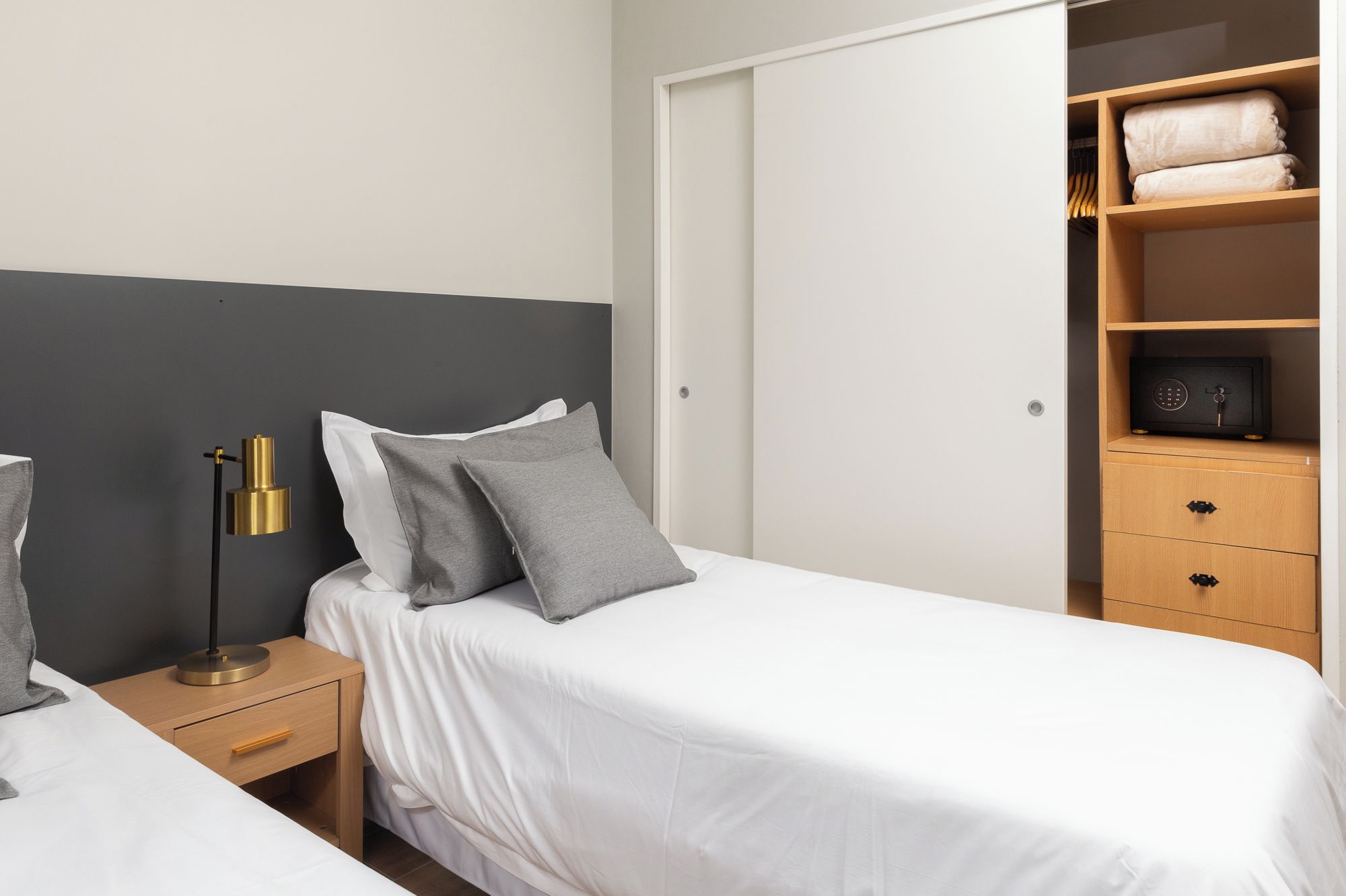 Ein Schlafzimmer mit einem Bett, Nachttischen, einem Kleiderschrank und einem Regal mit Handtüchern.