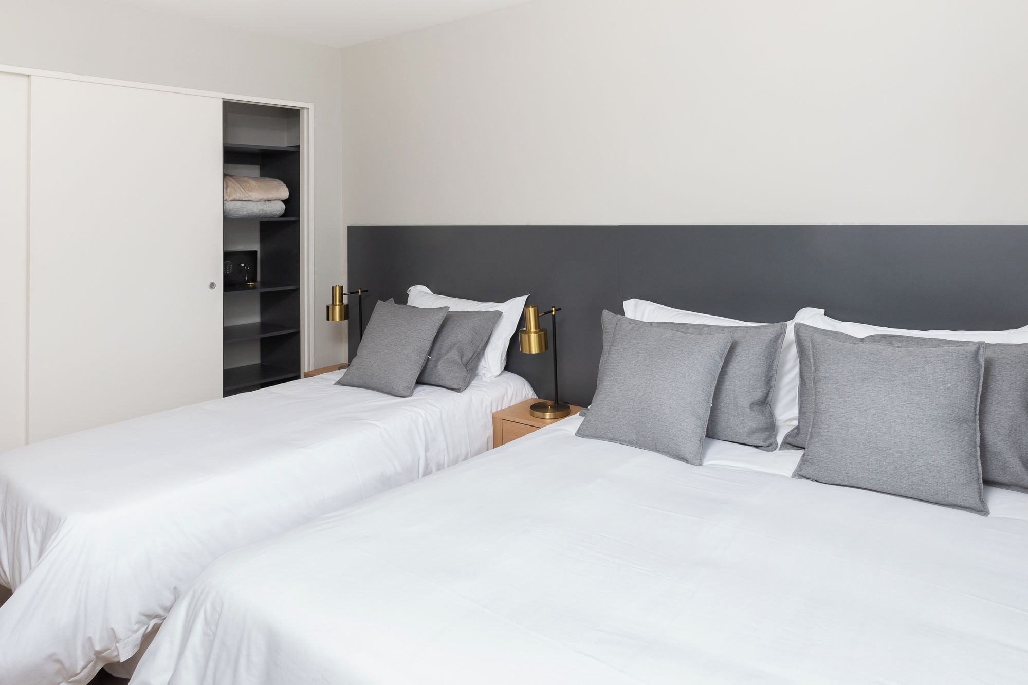 Une chambre d’hôtel avec deux lits, une armoire et une table de chevet avec des lampes.