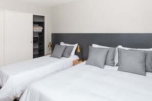 Une chambre d’hôtel avec deux lits, une armoire et une table de chevet avec des lampes.