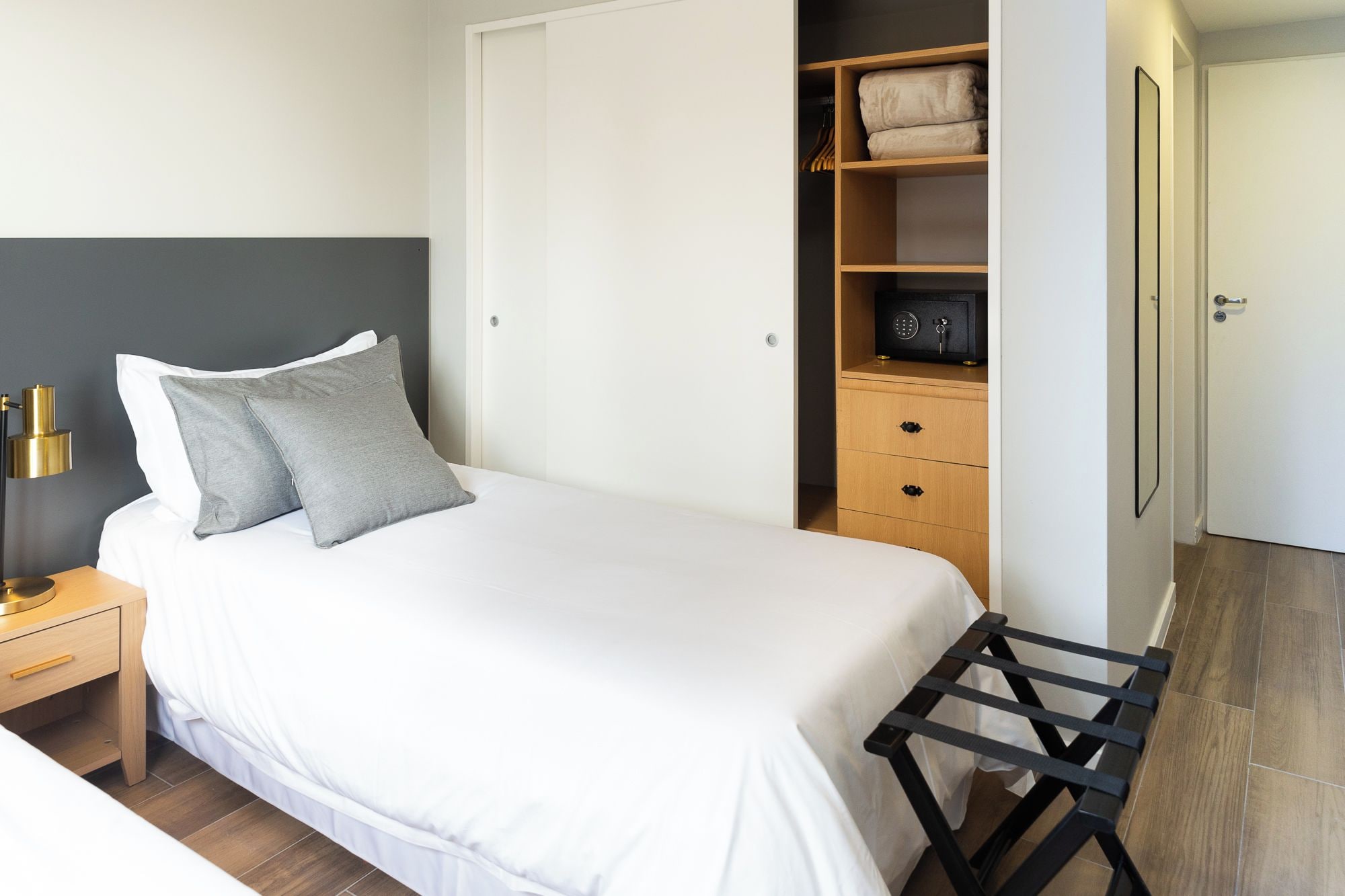 Une chambre à coucher avec un lit, une table de chevet, une lampe, une armoire et un miroir.