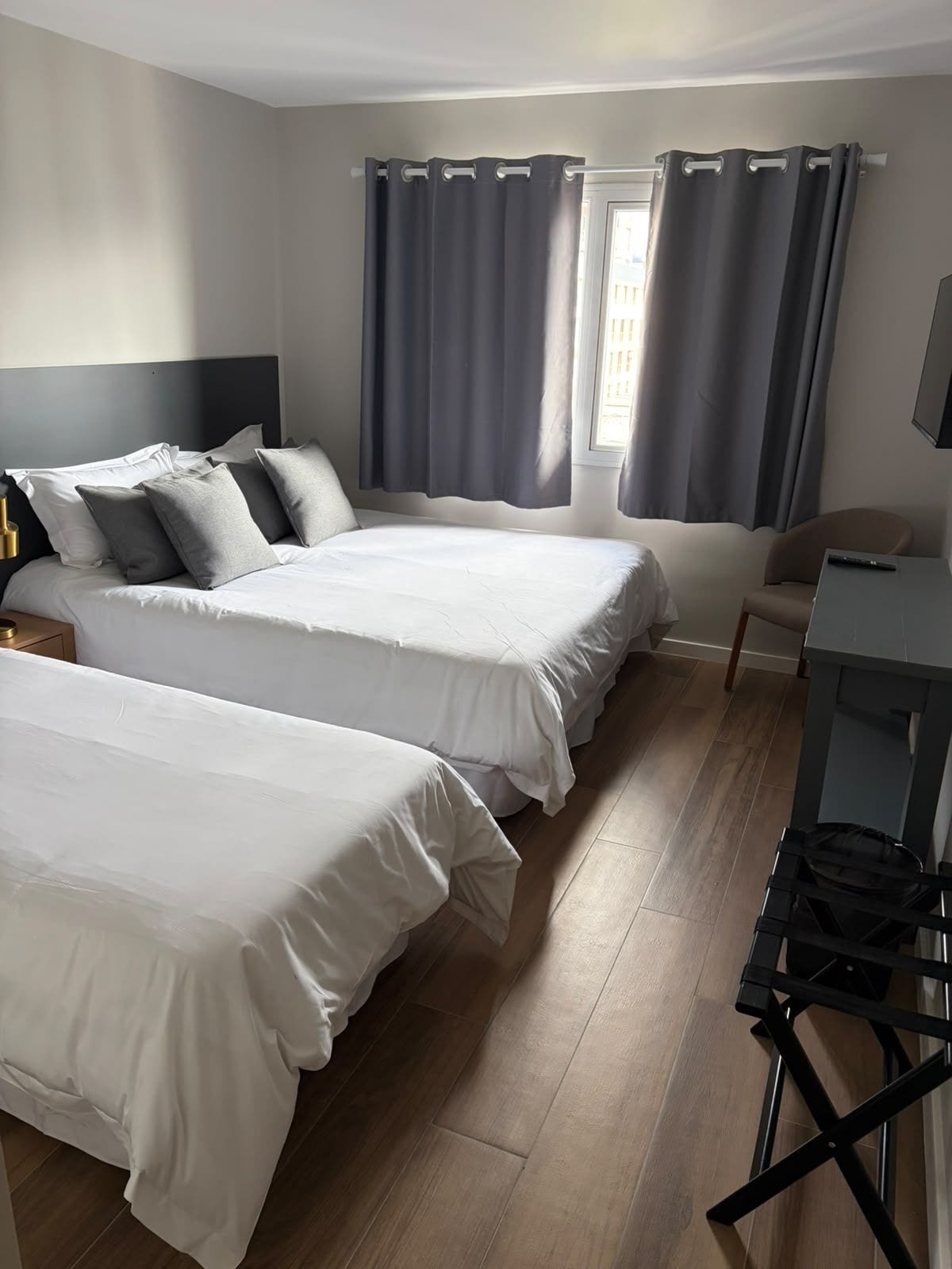 Une chambre d’hôtel avec deux lits, un bureau, une chaise et un téléviseur.